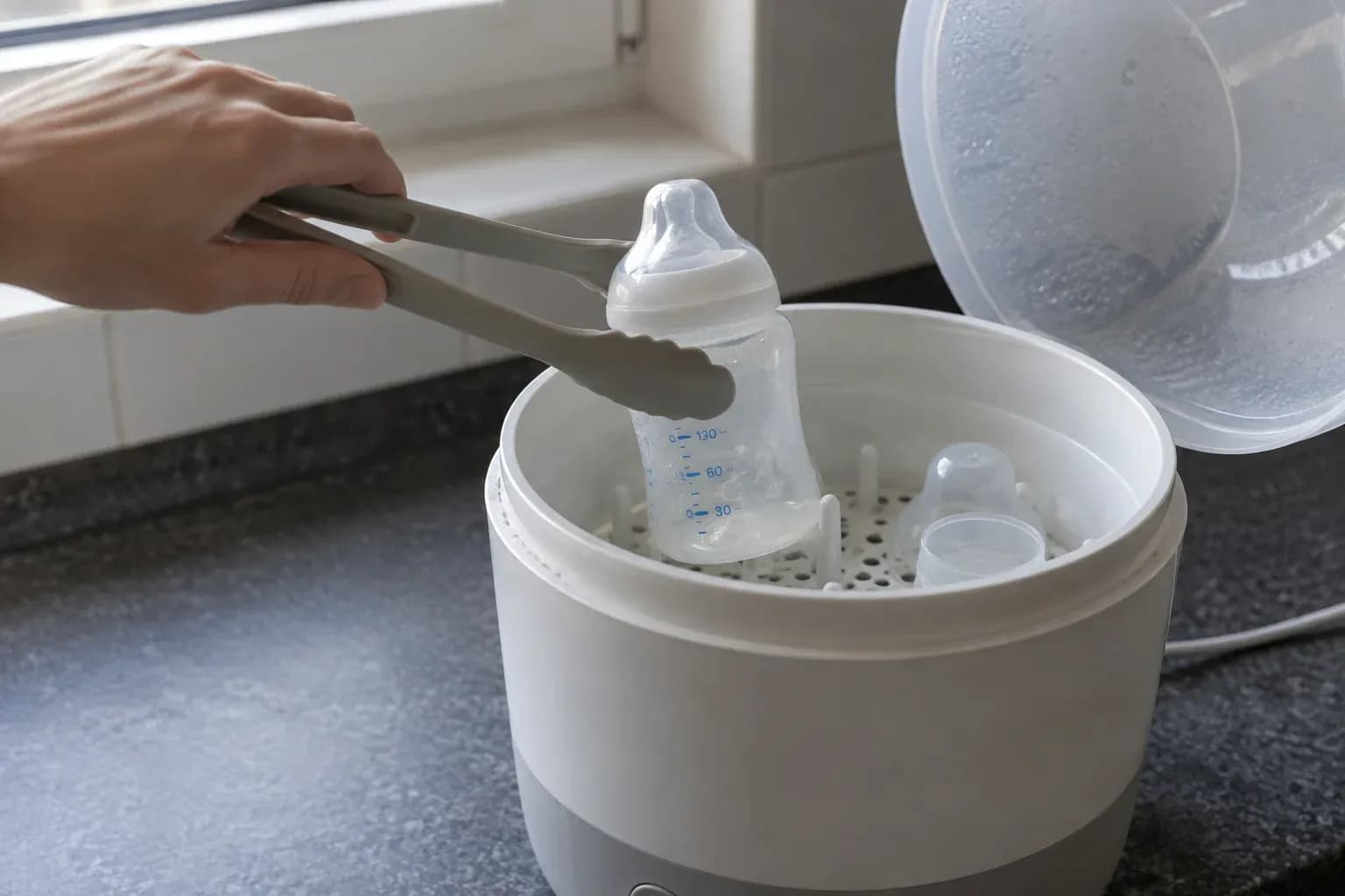Vyndávání kojenecké lahve kleštěmi ze sterilizátoru